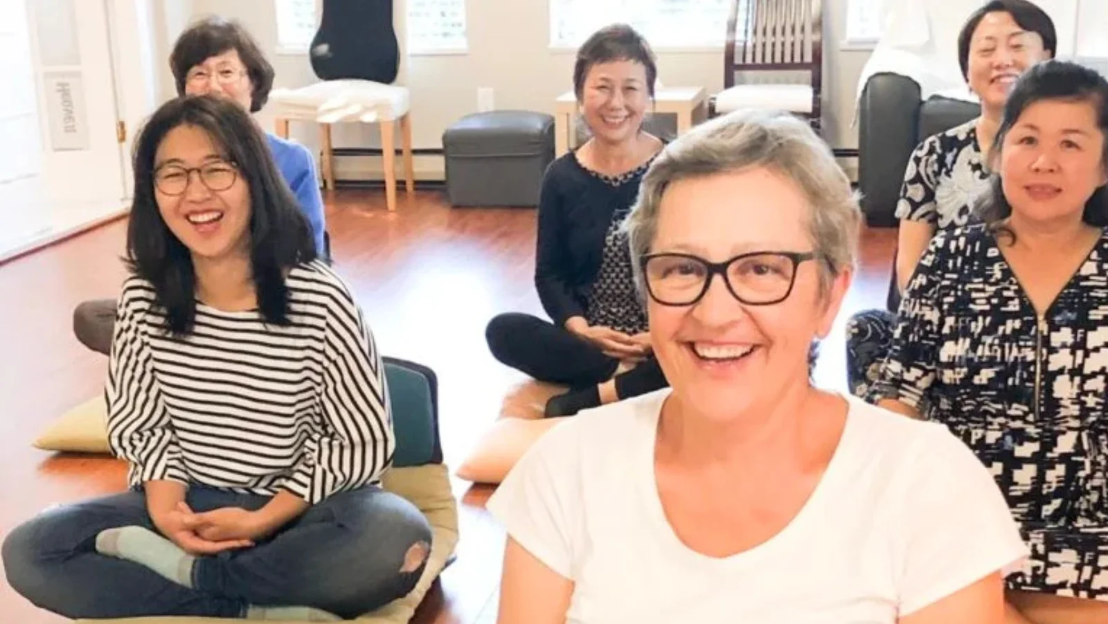 Members smiling together during a group meditation class